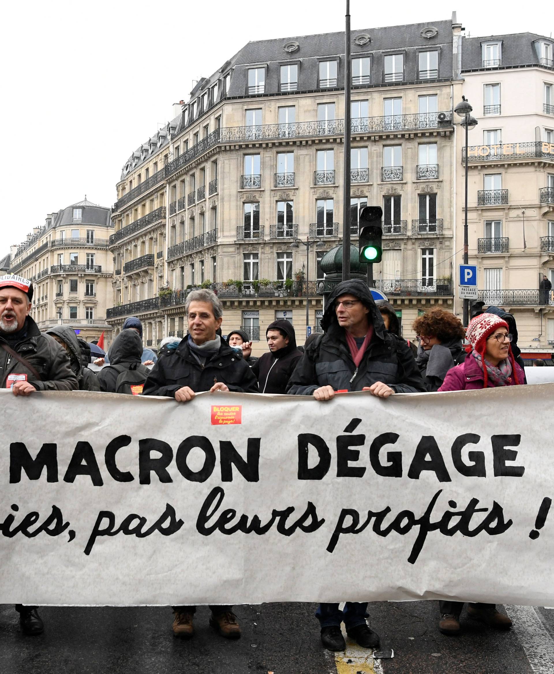 People hold a banner which reads "Macron get out, our lives, not our profits" as they demonstrate in a street during a national day of protest by the "yellow vests" movement in Paris