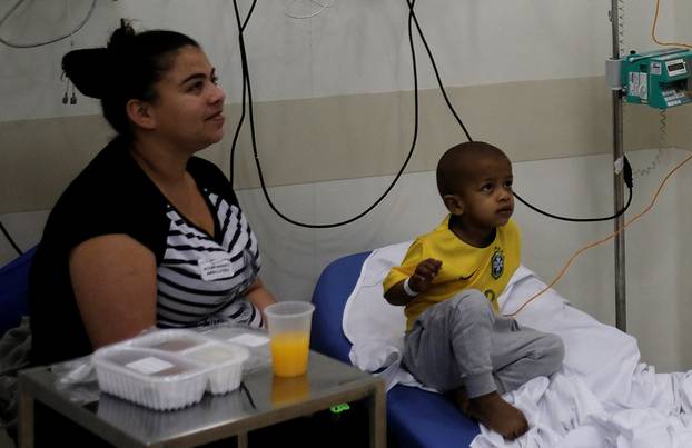 Brazilian patient Lucas wears a Brazil national soccer team t-shirt next to his mother Claudia as they watch the 2018 World Cup soccer match between Brazil and Mexico at the Cancer Itaci Hospital in Sao Paulo