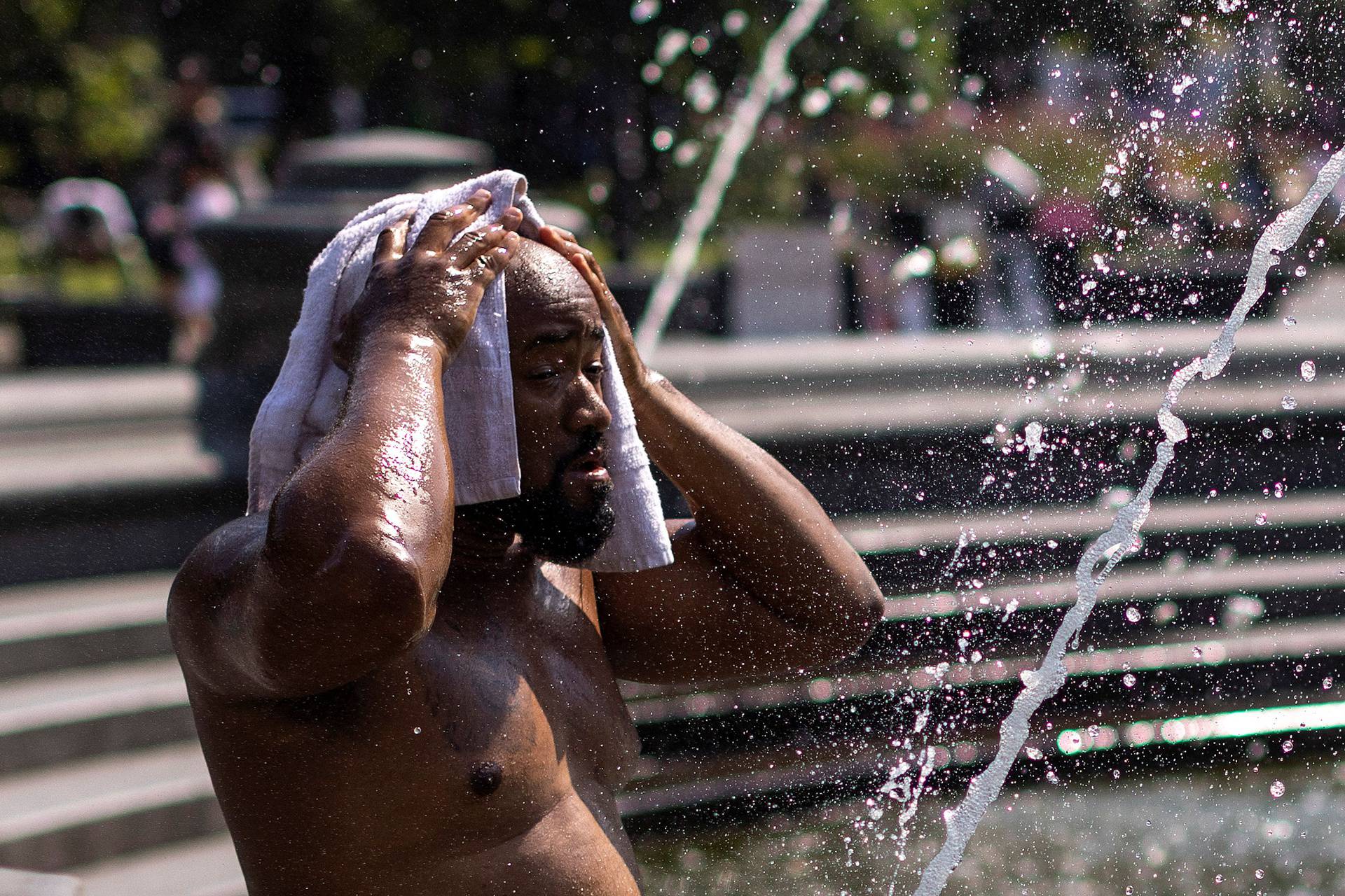 A man cools off during a hot and humid day at Washington Square park in New York City