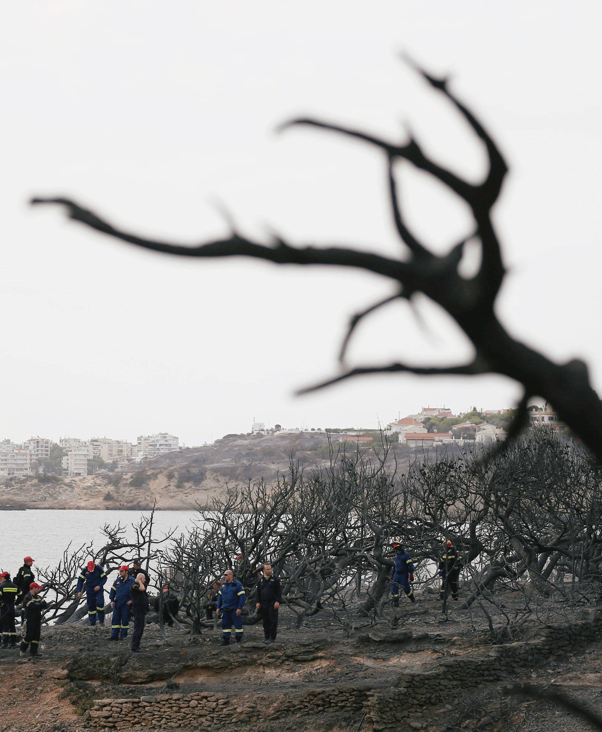 Firefighters look for missing persons after following a wildfire at the village of Mati, near Athens