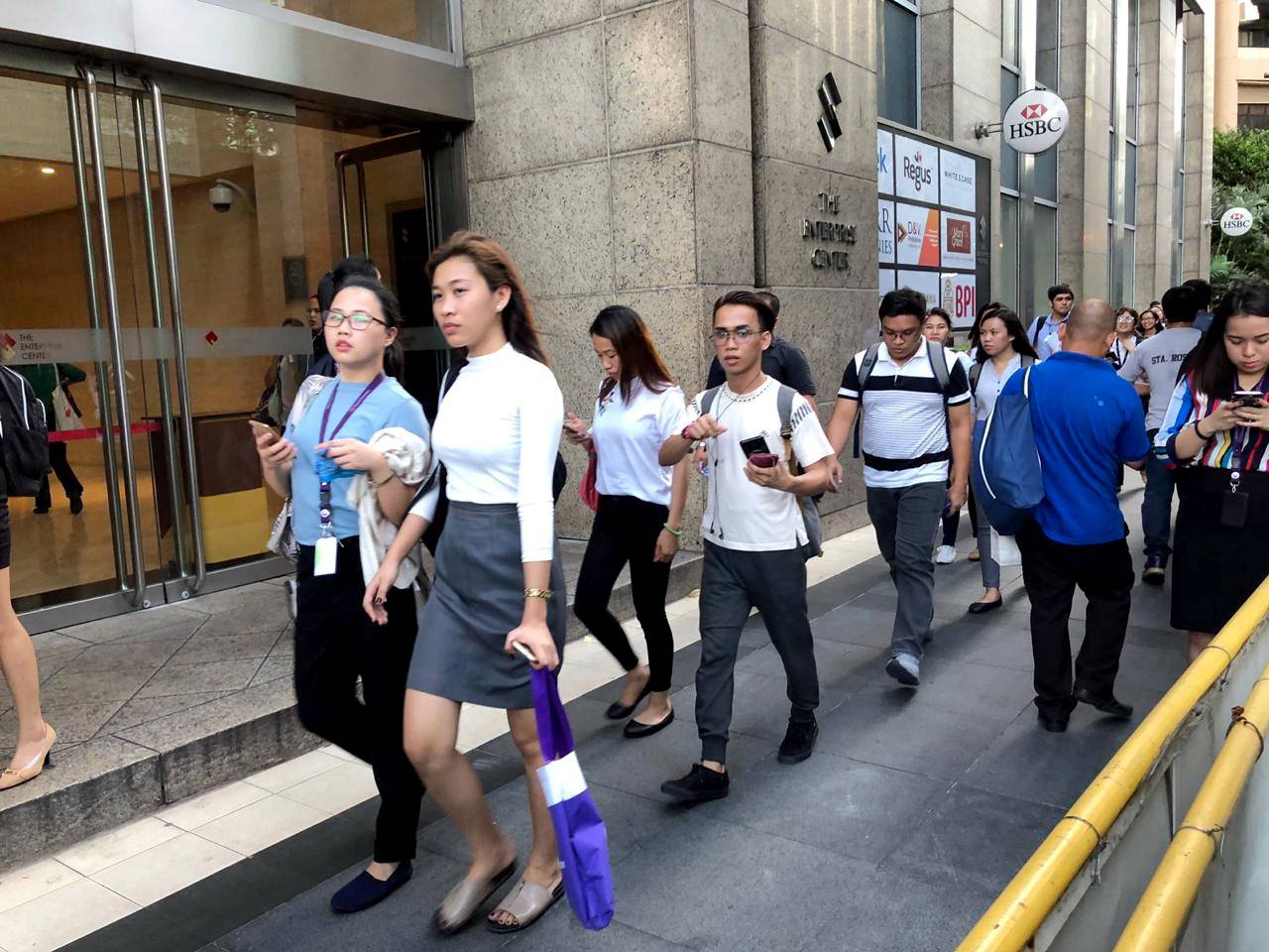 Employees walk outside after being evacuated from the office building after an earthquake in Makati City