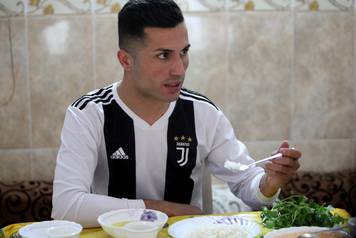 Biwar Abdullah, 25, an Iraqi Kurdish local footballer, who looks like the football player Cristiano Ronaldo, eats at his home in the district of Soran, northeast of Erbil