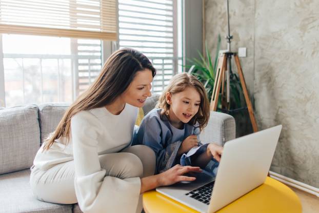 Mother,And,Daughter,Siting,On,The,Couch,And,Using,Laptop