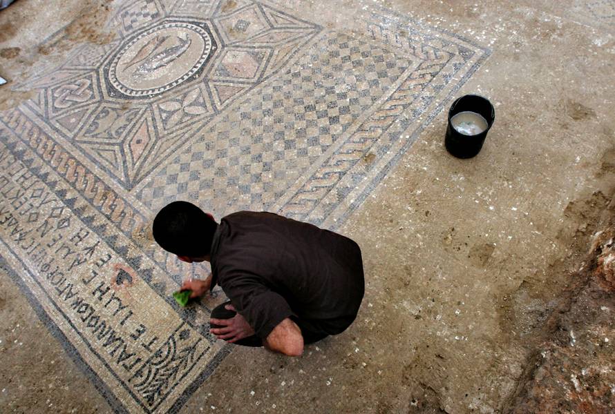 FILE PHOTO: A prison inmate cleans a mosaic on the floor of ancient prayer hall that was discovered on the site of Megiddo Prison in northern Israel