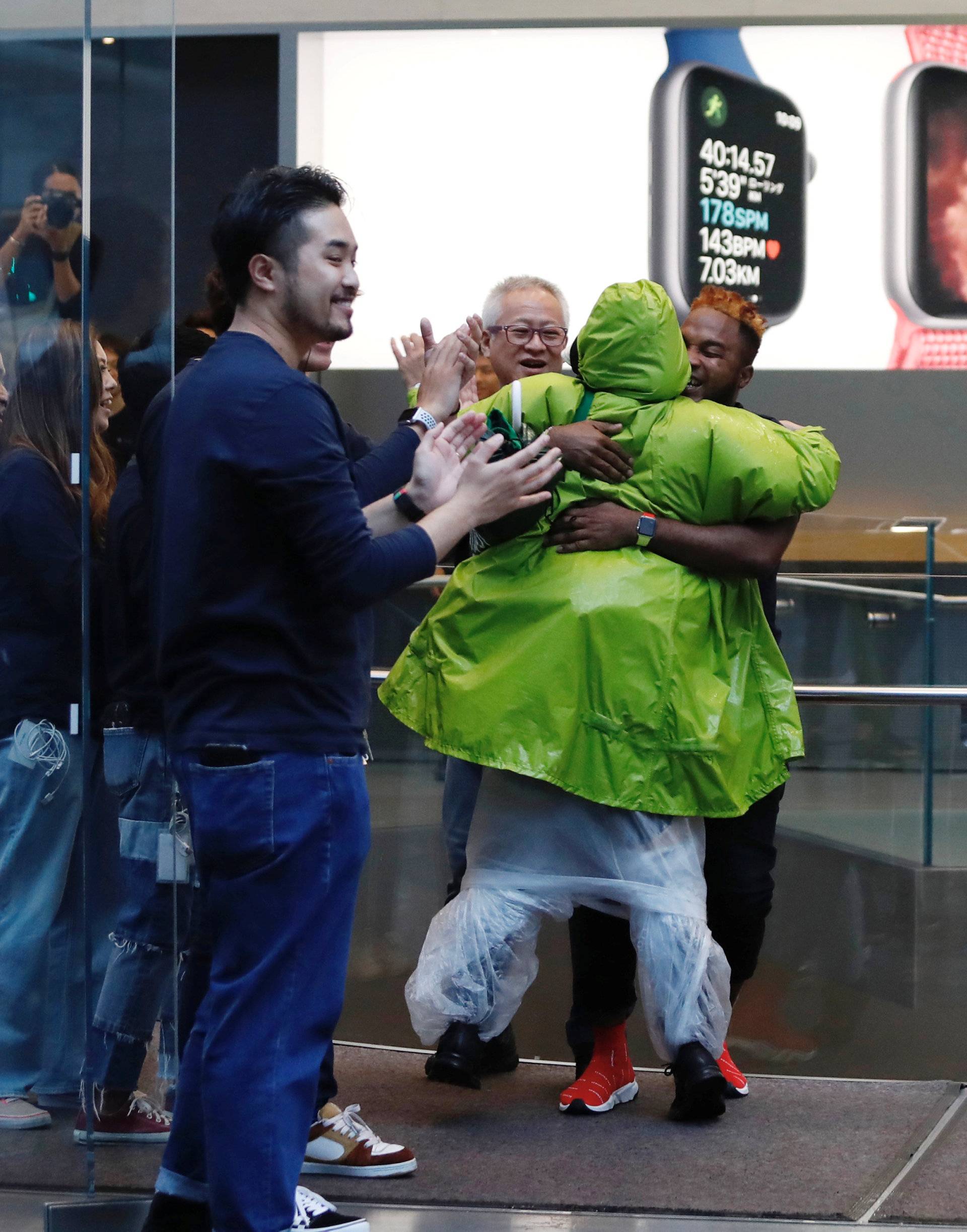 Apple Store staff greets customers who have been waiting in line to purchase Apple's new iPhone XS and XS Max in Tokyo