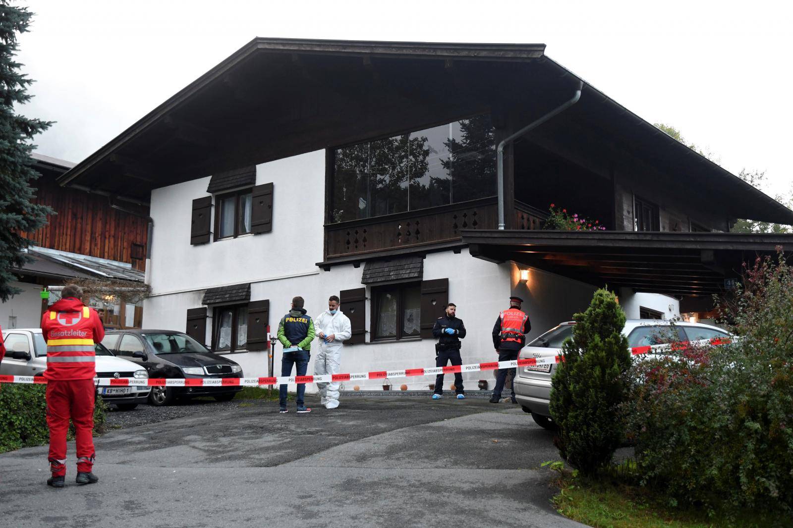 Police officers and rescue workers stand in front of a house where, according to police, five people were found dead in Kitzbuehel