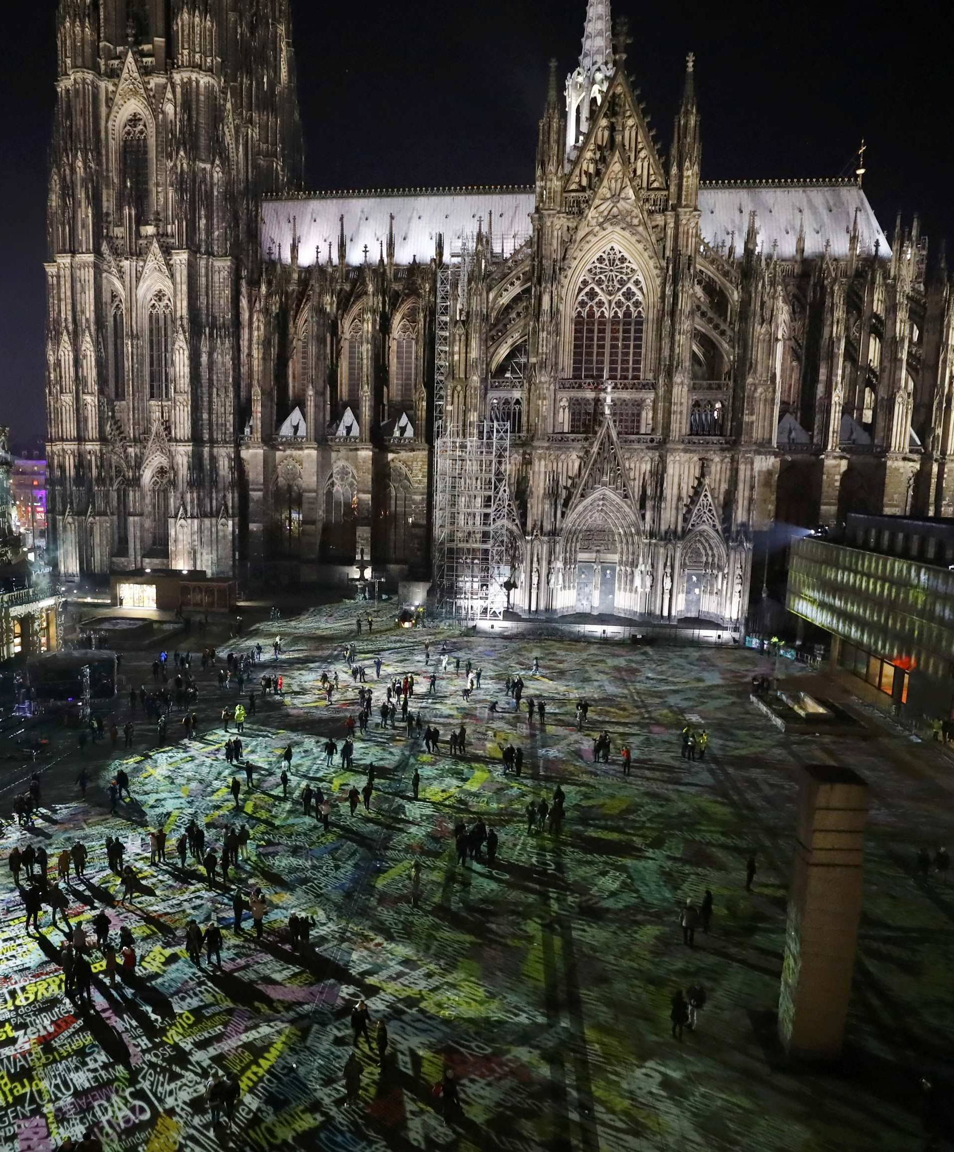 People walk over the laser installation "Time Drifts Cologne"  before New Year celebrations in Cologne