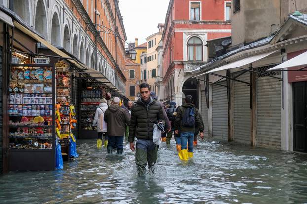 People walk in the flooded street during a period of seasonal high water in Venice