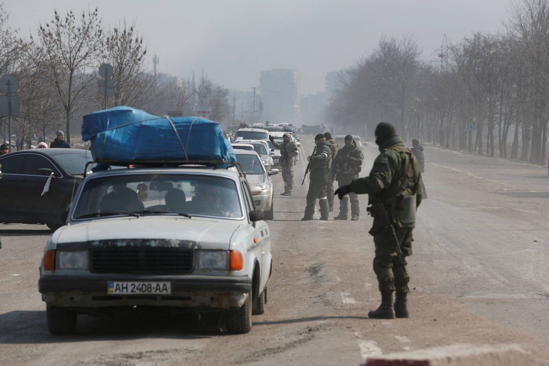 Service members of pro-Russian troops stand guard at a checkpoint in the besieged city of Mariupol