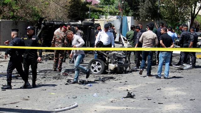 Iraqi security forces inspect the site of a car bomb attack in Baghdad