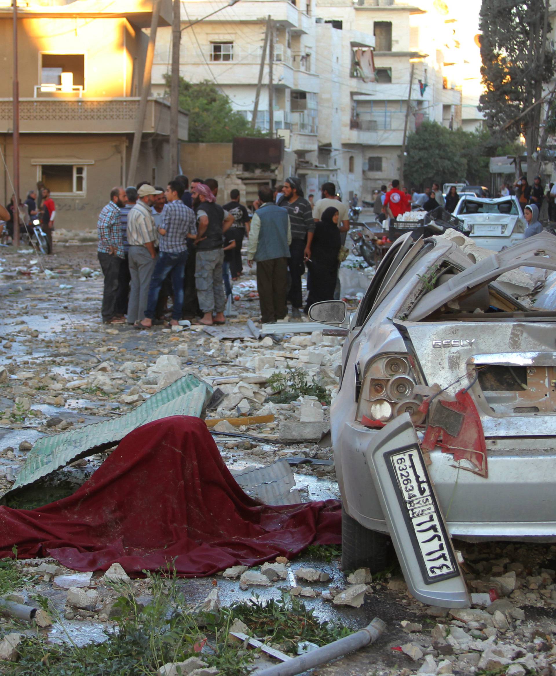 People inspect the damage at a site hit by airstrikes in Idlib