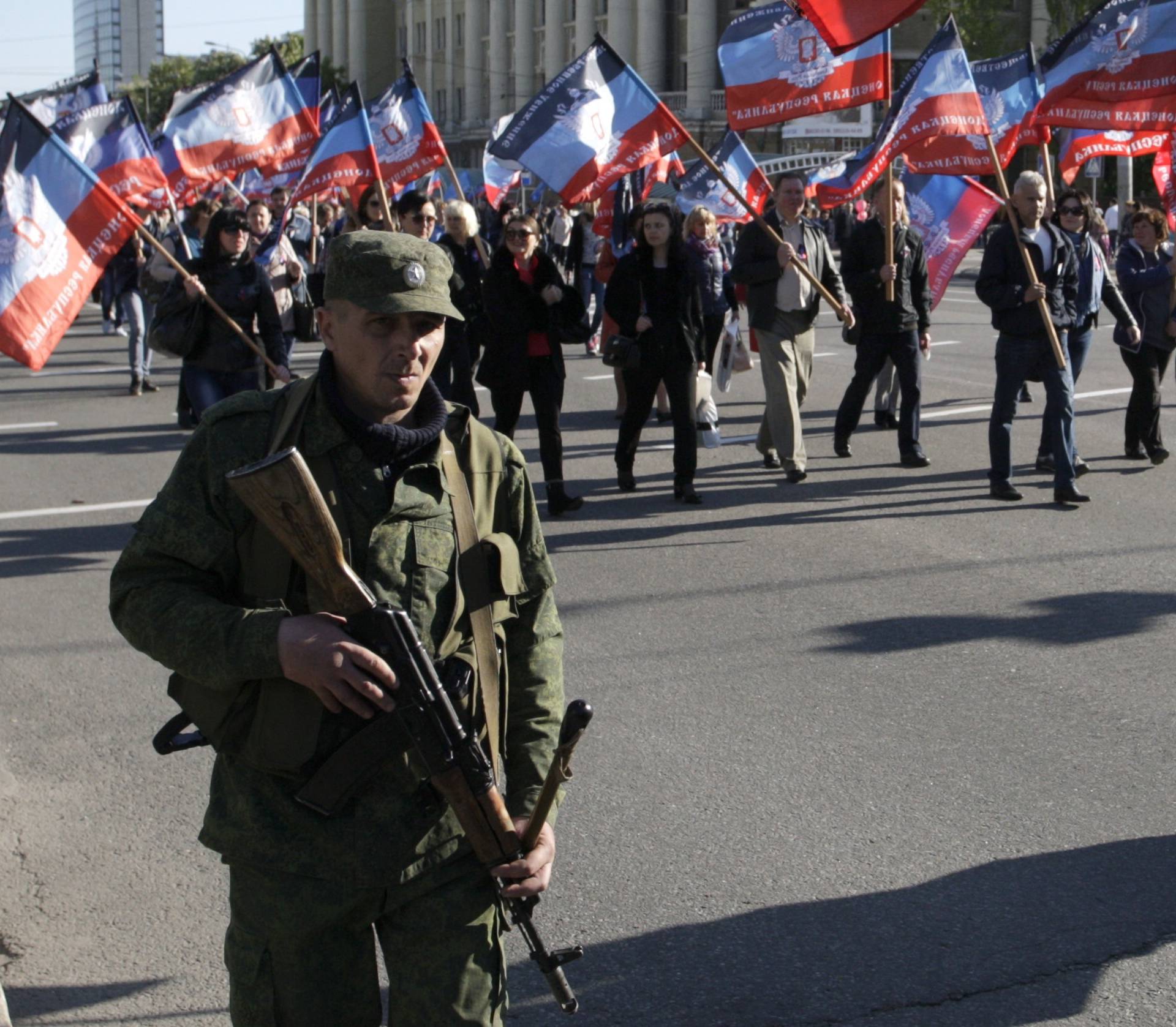 People carry flags of self-proclaimed Donetsk People's Republic as they attend rally marking third anniversary of referendum on secession in rebel-controlled city of Donetsk