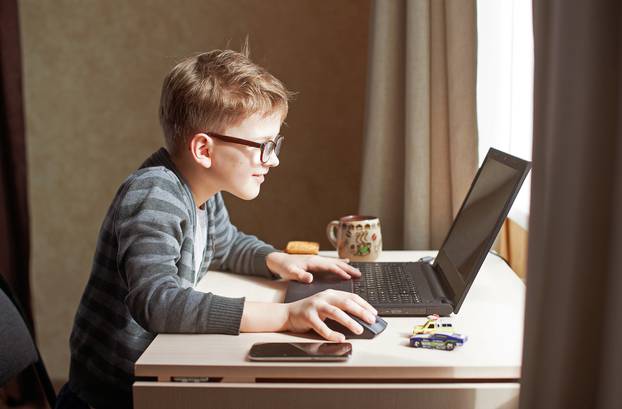 Happy,Boy,Sitting,At,His,Desk,With,Laptop,Computer