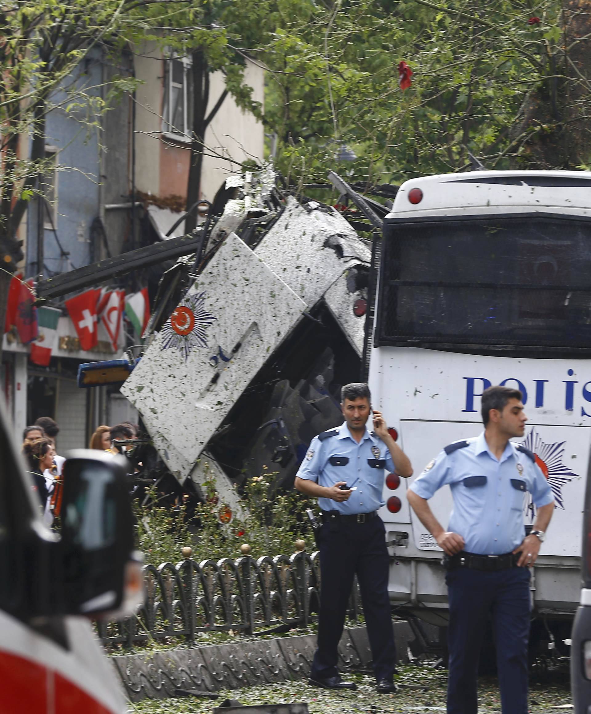 A policeman uses his phone near a Turkish police bus which was targeted in a bomb attack in a central Istanbul district