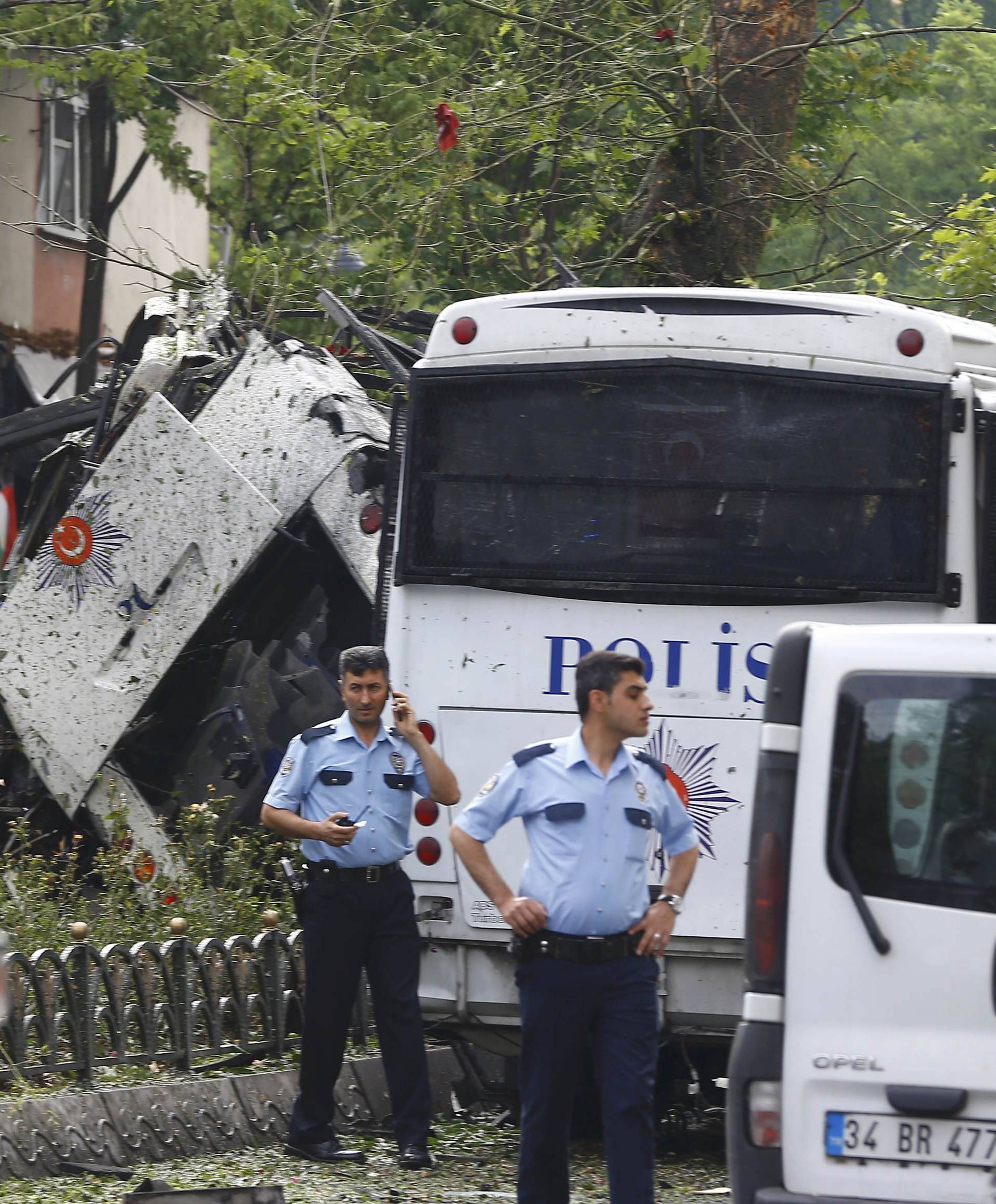 A policeman uses his phone near a Turkish police bus which was targeted in a bomb attack in a central Istanbul district