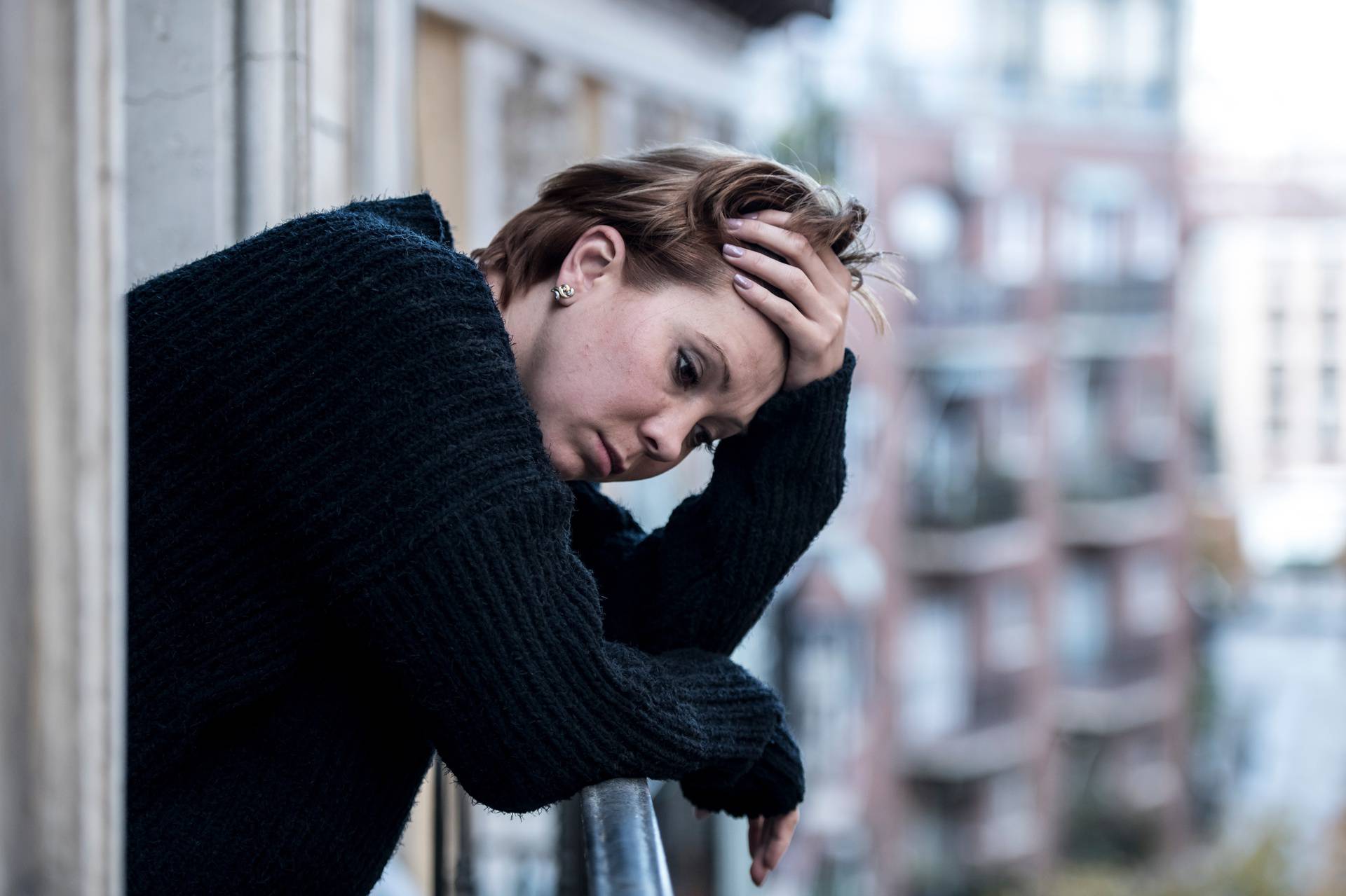 young beautiful woman thinking and feeling sad suffering depression at urban city background home balcony