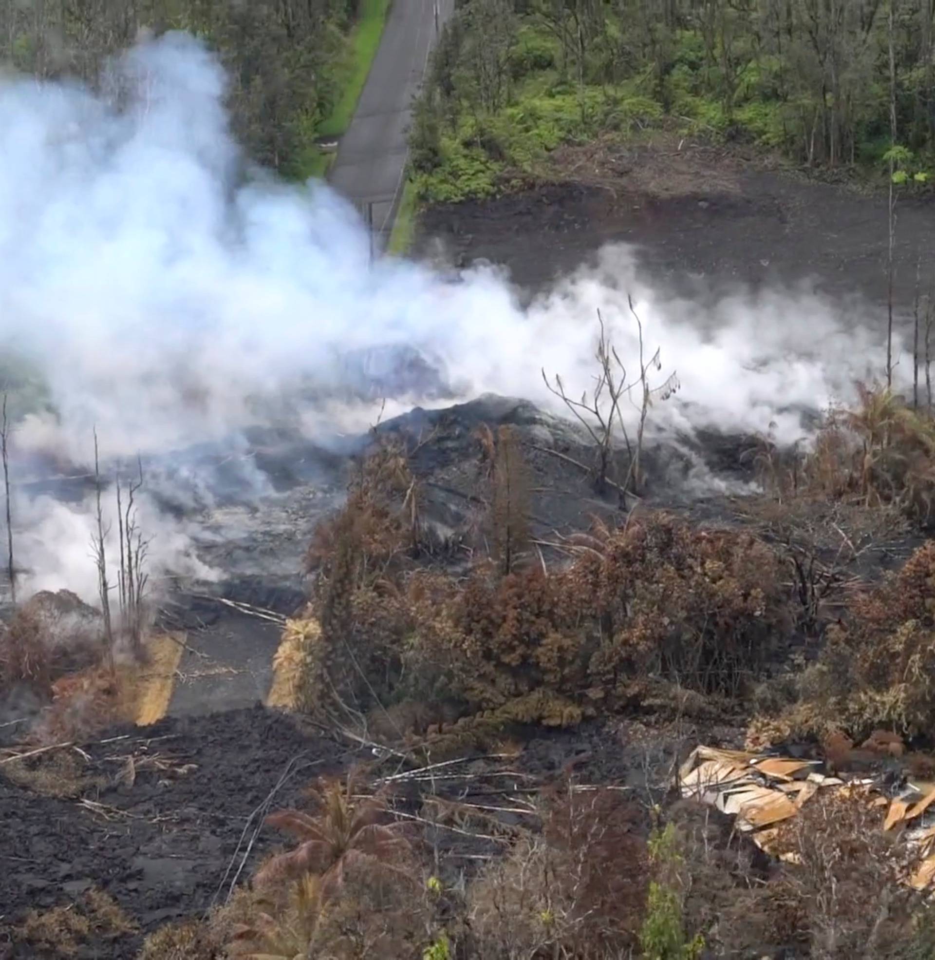 Aerial image of molten rock flowing and bursting to the surface threatening homes in a rural area in Hawaii