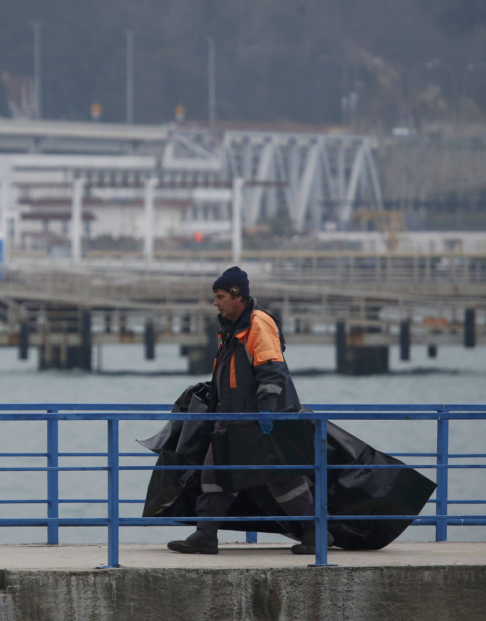Russian Emergencies Ministry member carries plastic bags while walking on pier near crash site of Russian military Tu-154 plane in Black Sea in Sochi suburb of Khosta
