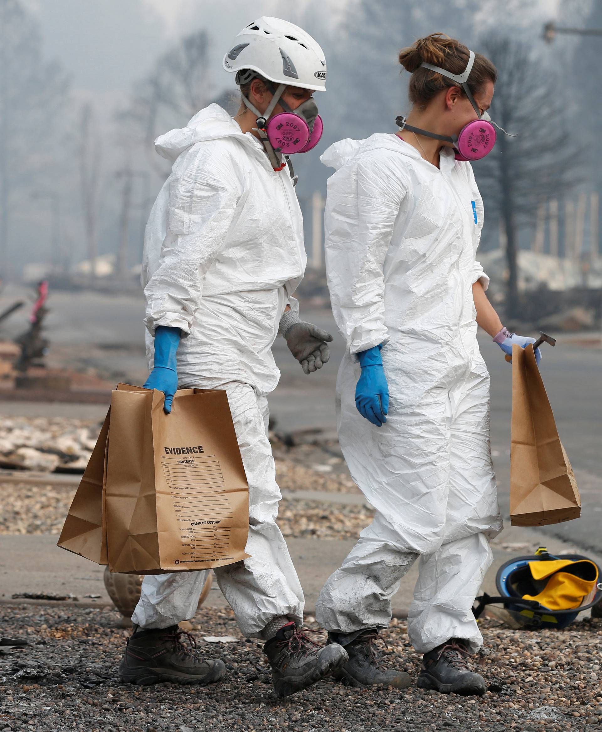 Forensic anthropologists Kyra Stull (C) and Tatiana Vlemincq (R) recover human remains from a trailer home destroyed by the Camp Fire in Paradise