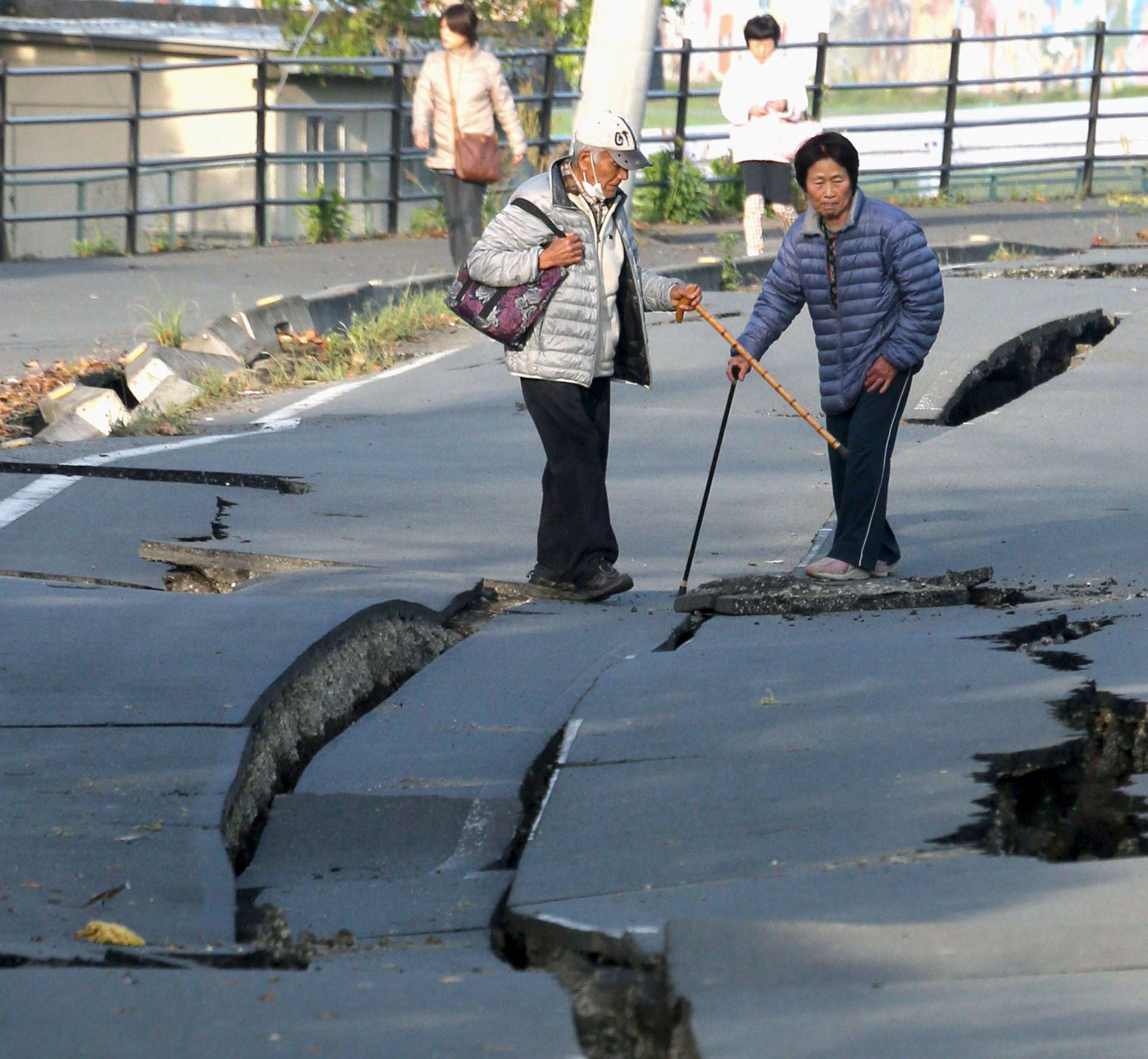 Local residents look at cracks caused by an earthquake on a road in Mashiki town
