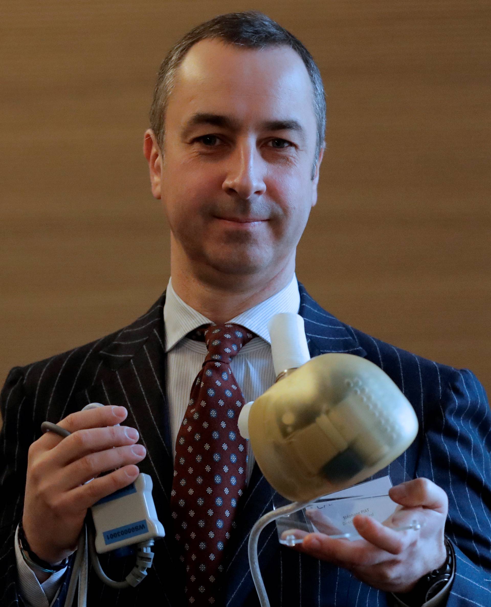 Carmat Chief Executive Officer Stephane Piat holds an artificial heart as he poses after the company's news conference in Paris