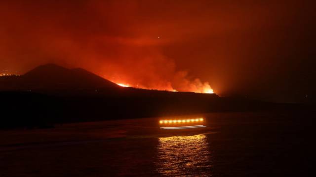 Coastguards pass as lava is seen arriving at the sea following the eruption of a volcano, seen from the Port of Tazacorte