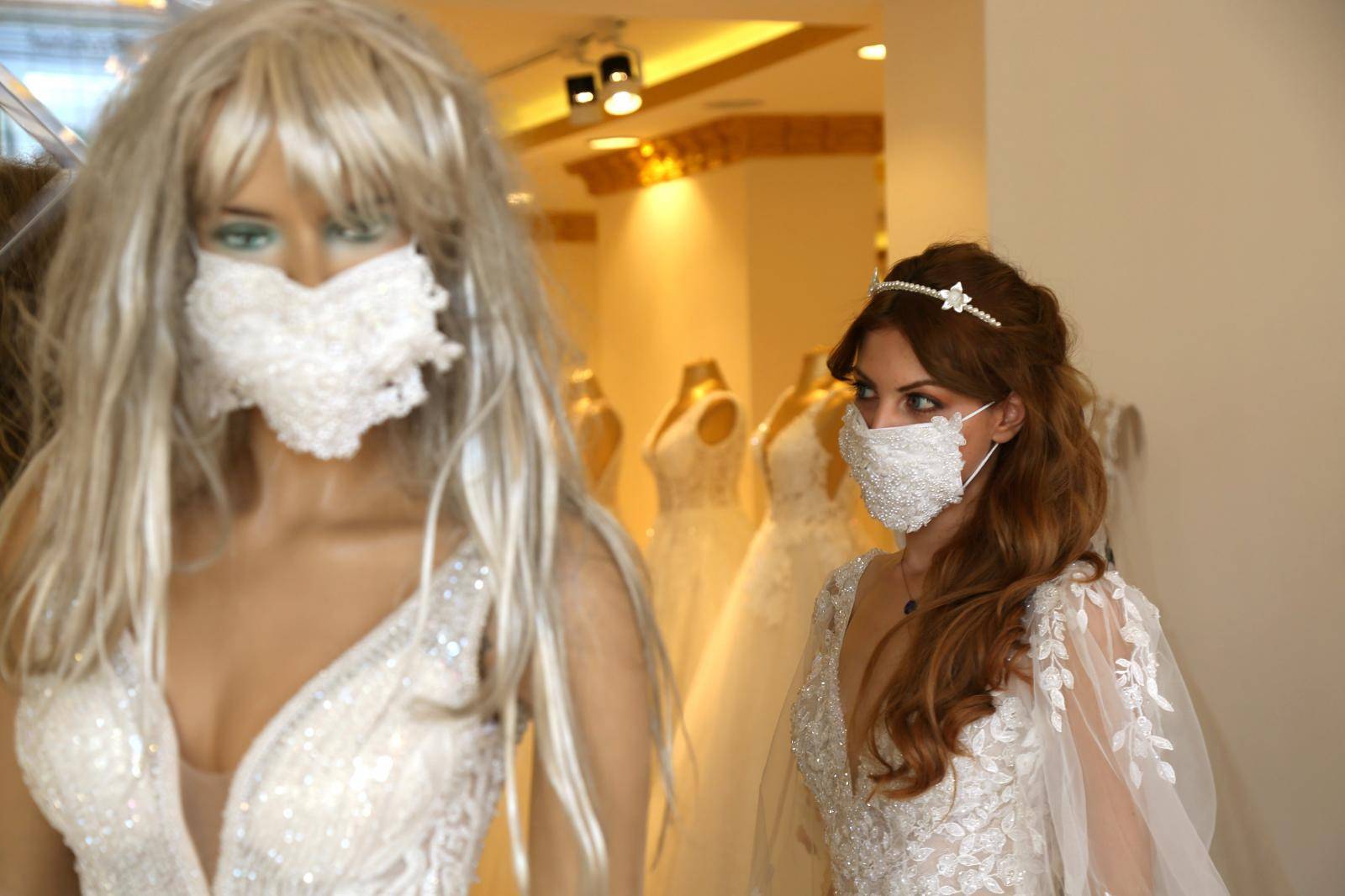 An employee presents a wedding dress with a mask at the Mezopotamya bridal gowns shop in Diyarbakir