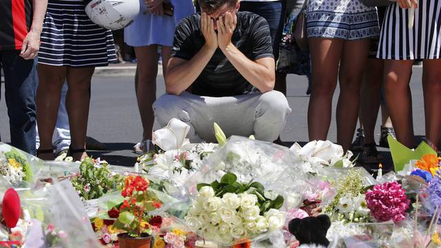 A man reacts near flowers placed in tribute to victims, two days after an attack by the driver of a heavy truck who ran into a crowd on Bastille Day killing scores and injuring as many, in Nice