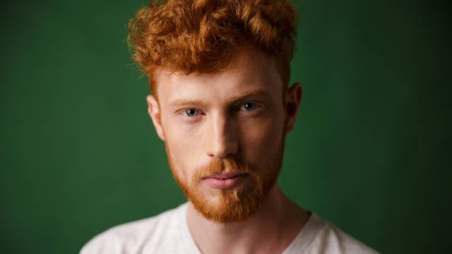 Close-up portrait of curly redhead young man with beard