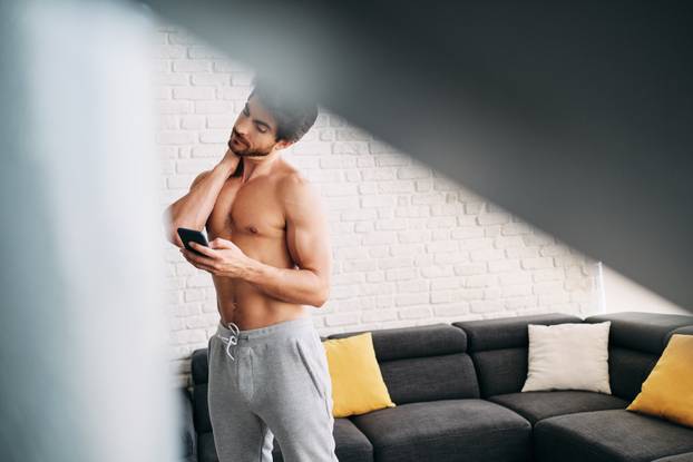 Man Working Out At Home With App On Mobile Phone