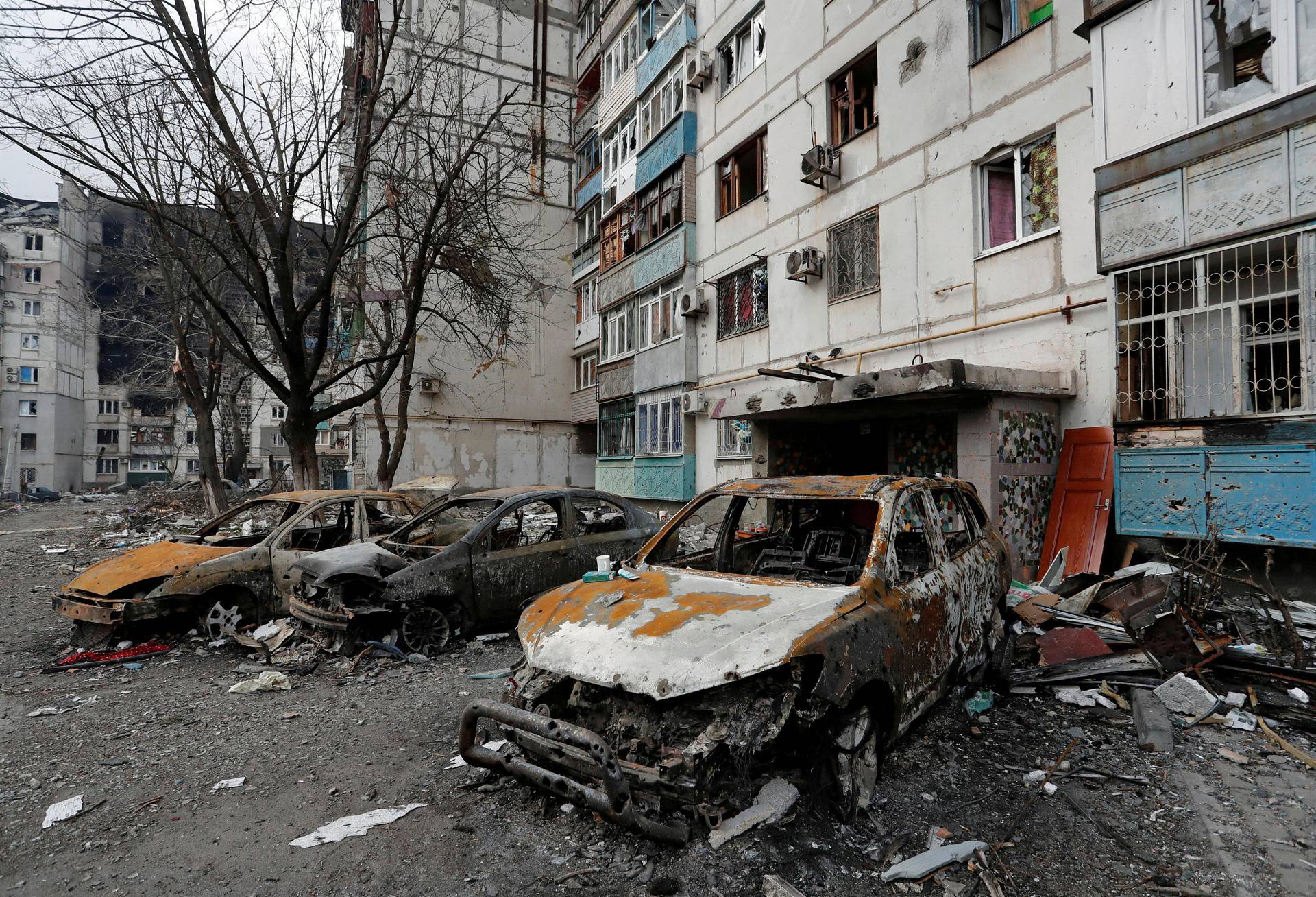 FILE PHOTO: Destroyed cars are seen in front of a damaged apartment building in the besieged city of Mariupol