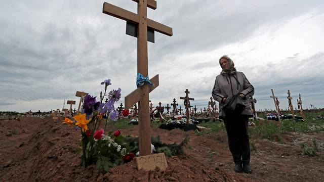 A woman visits her son's grave at a cemetery outside Mariupol