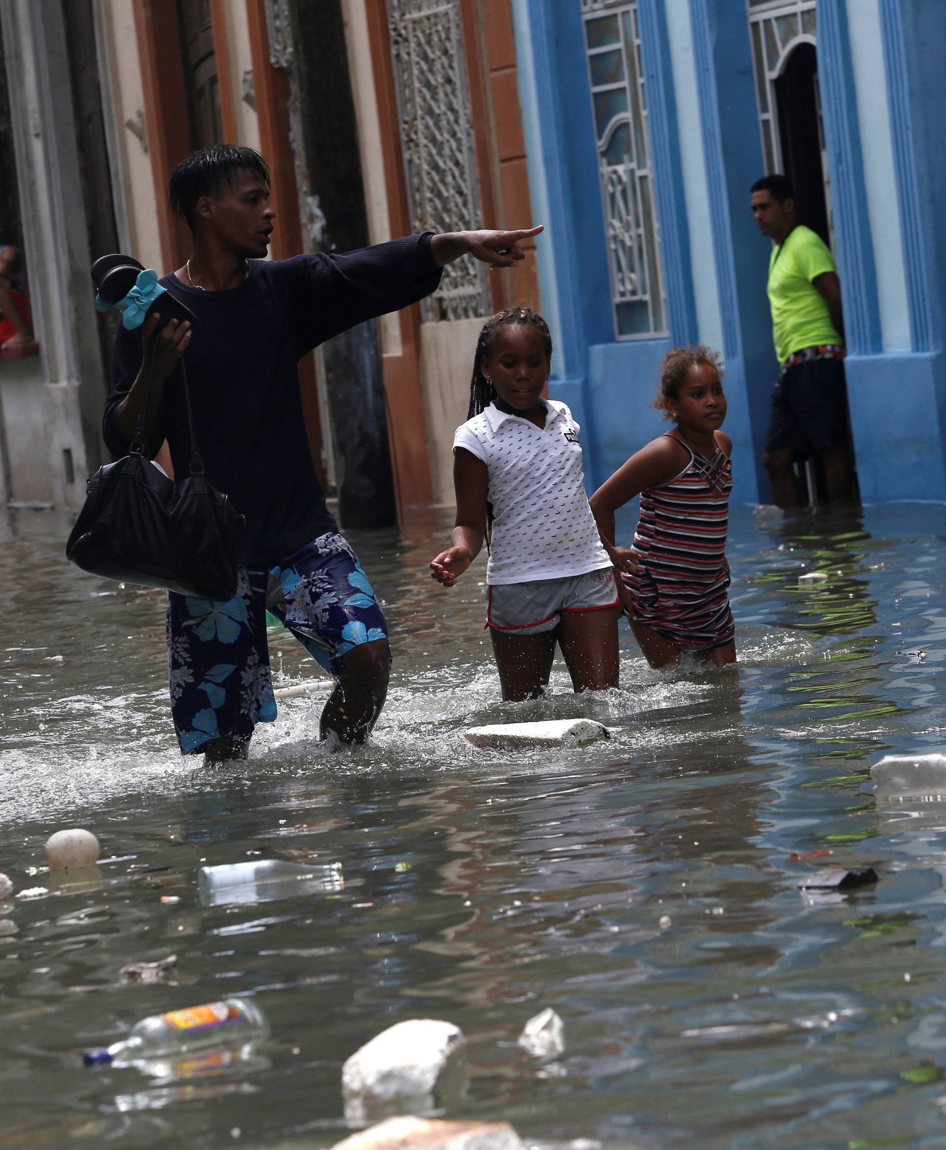 A man and two children wade through a flooded street,  after the passing of Hurricane Irma, in Havana