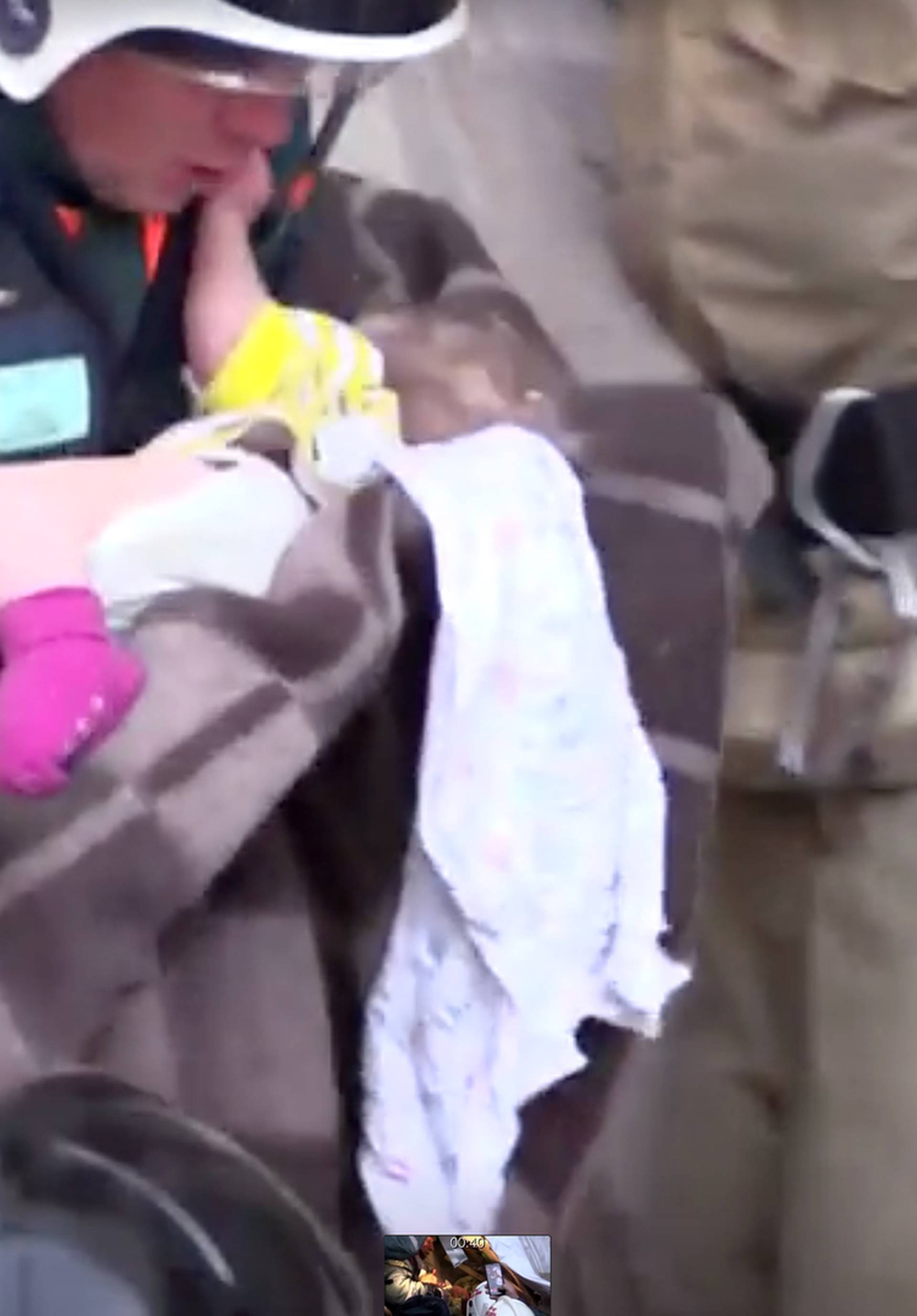 A still image taken from a video footage shows a rescuer carries a 10-month-old child found alive in the rubble of a Russian apartment block that partially collapsed after a suspected gas blast in Magnitogorsk