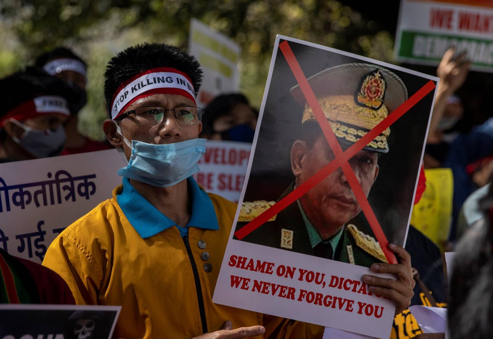 A Myanmar citizen living in India holds a poster of Myanmar's army chief Senior General Min Aung Hlaing with his face crossed out during a protest against the military coup in Myanmar, in New Delhi