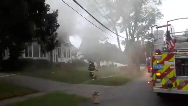 Still image from social media video footage by Boston Sparks shows firefighters working near a building emitting smoke after explosions in North Andover, Massachusetts