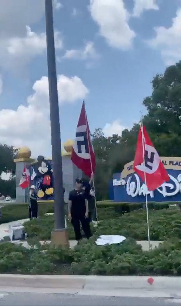 People displaying Nazi flags and symbols protest outside the entrance to Walt Disney World Resort in Orlando, FL
