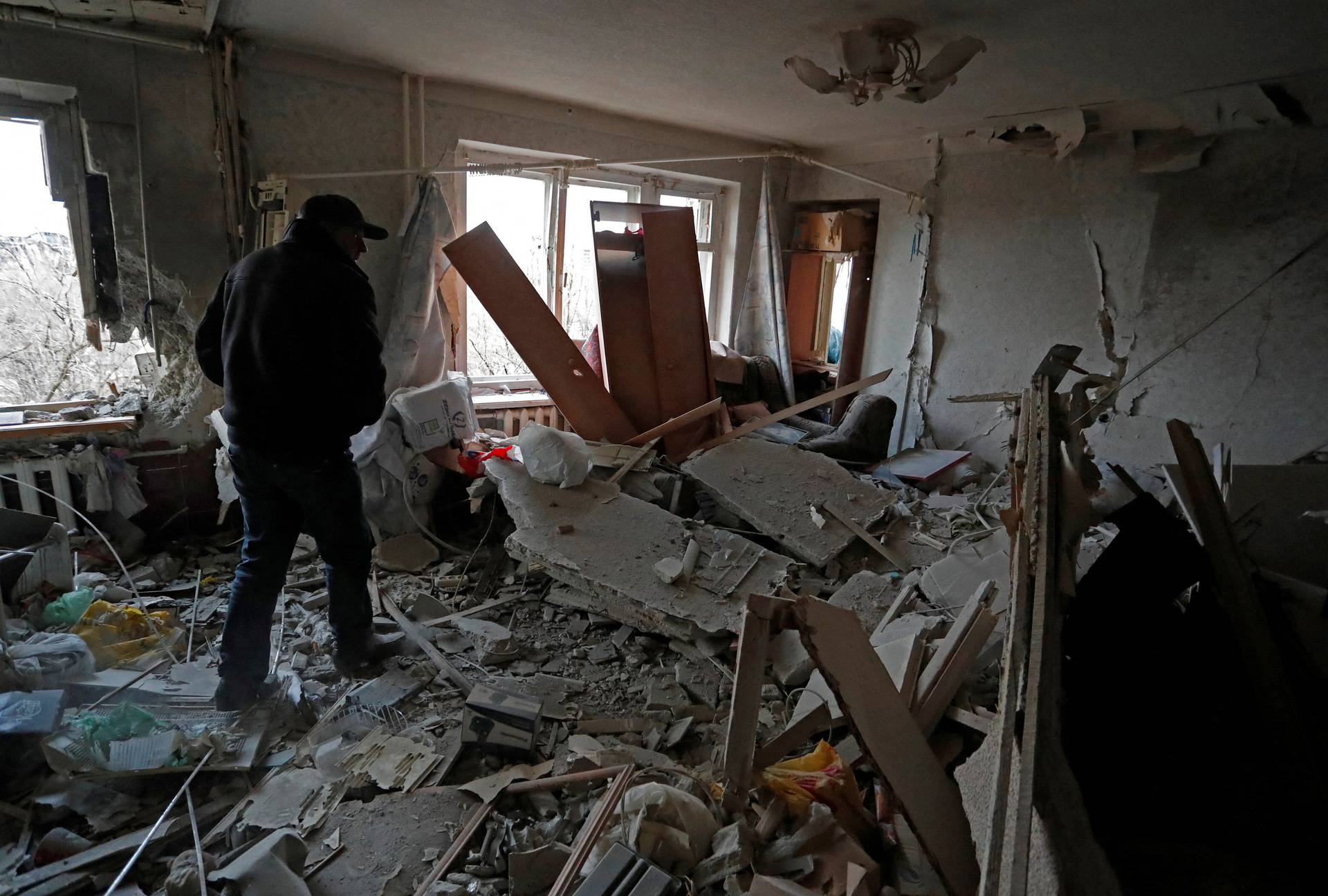 A local resident walks inside a damaged apartment in the besieged city of Mariupol