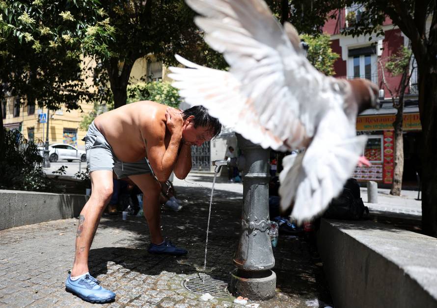 A man pours water over himself to cool off during a hot day amid a heatwave in Madrid, Spain