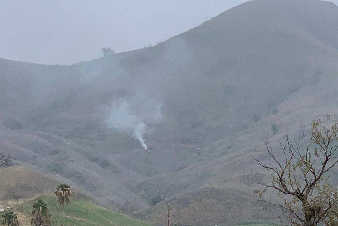 Smoke rises amid foggy weather from the site of a helicopter crash that killed former NBA star Kobe Bryant along a hillside in Calabasas
