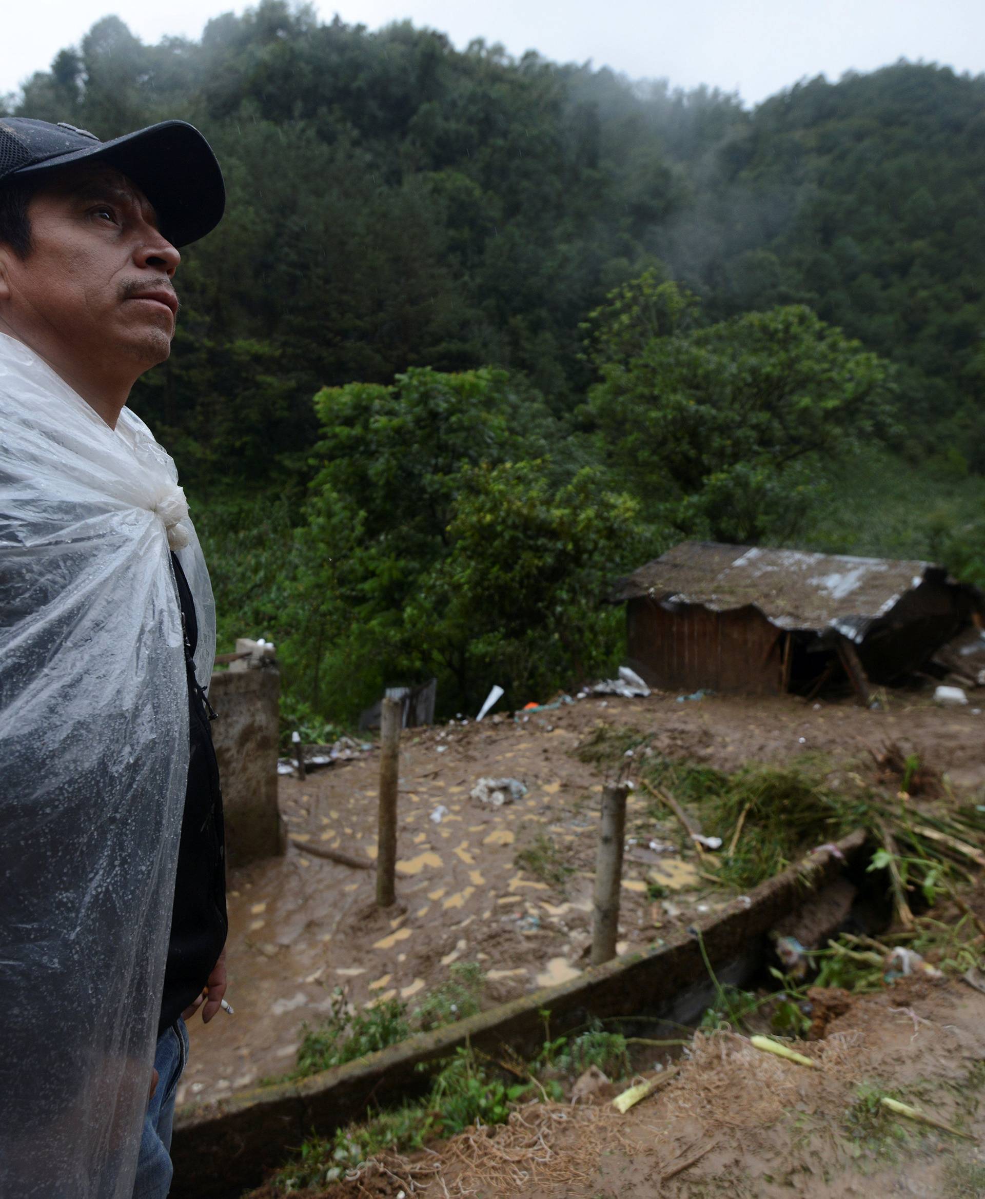 A resident stands near a house where three members of a family died after a mudslide following heavy showers caused by the passing of Tropical Storm Earl in the town of Temazolapa