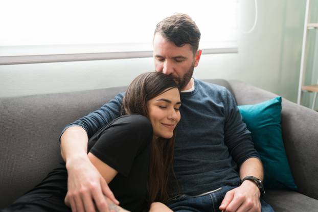Happy couple kissing while resting on the sofa
