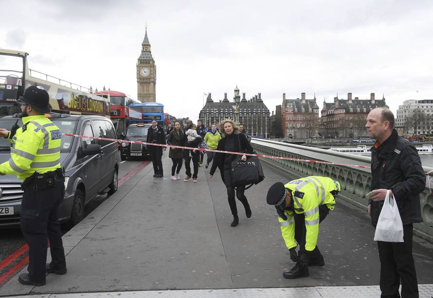 A woman ducks under a police tape after an incident on Westminster Bridge in London