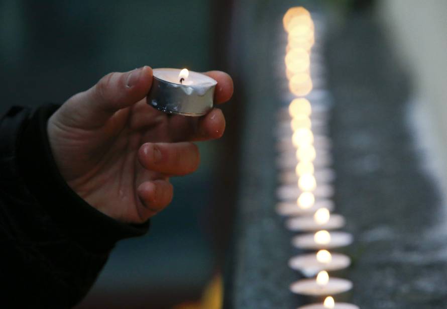 Man lights candle in memory of passengers and crew members of Russian military Tu-154 plane crashed into Black Sea, outside headquarters of Alexandrov Ensemble in Moscow