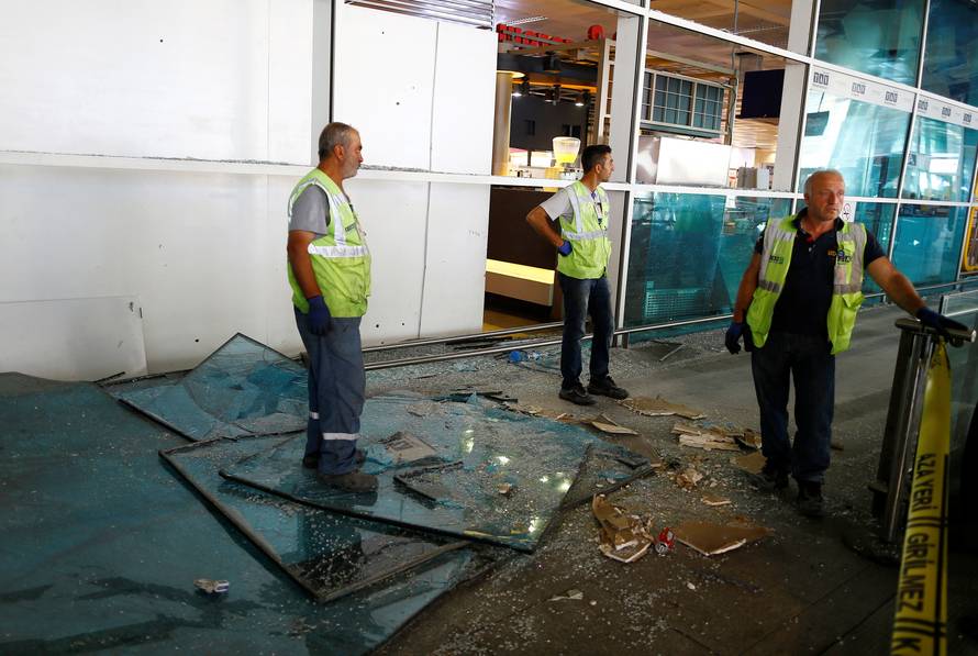 Workers stand near debris from yesterday's blasts as they take a break at Turkey's largest airport, Istanbul Ataturk