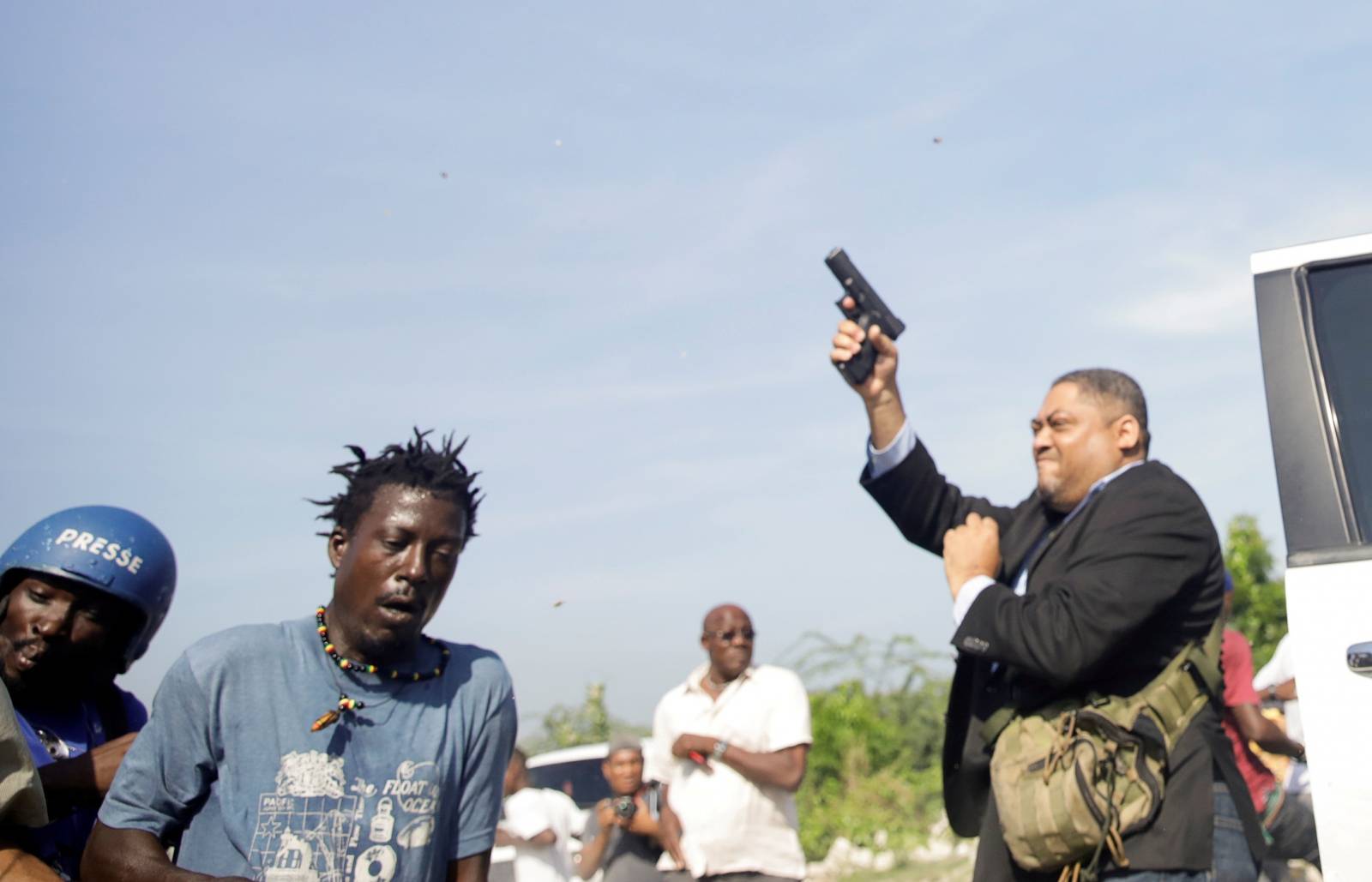 People run as Haiti's Senator Jean Marie Ralph Fethiere holds a gun in Port-au-Prince