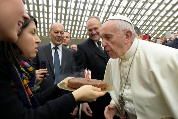 Pope Francis blows candles on a birthday cake, received from faithful to celebrate his 80th birthday on Saturday, during his Wednesday general audience at the Vatican