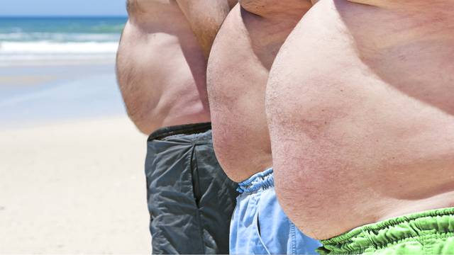 Close up of three obese fat men of the beach