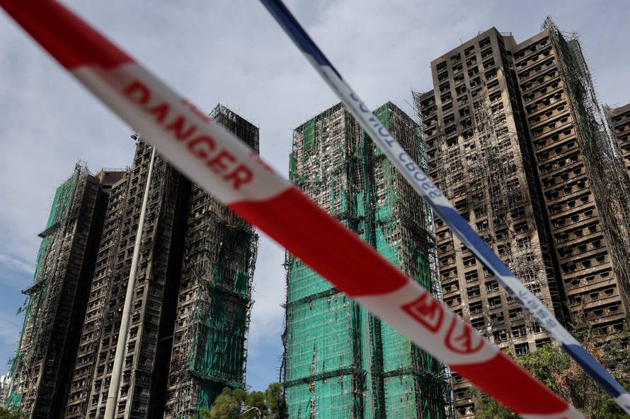 Police cordons are placed at the scene of the Wang Fuk Court housing estate fire as mourners pay tribute to the victims, in Tai Po, Hong Kong