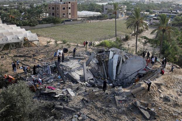 Palestinians gather around the remains of a house destroyed in an Israeli air strike in the southern Gaza Strip